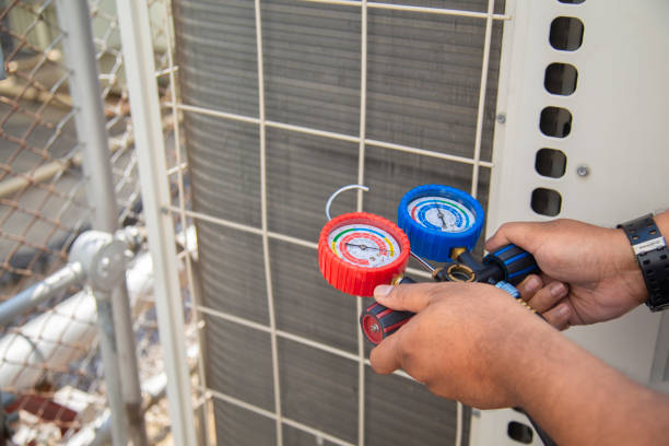 Technician checking air conditioning unit with red and blue pressure gauges