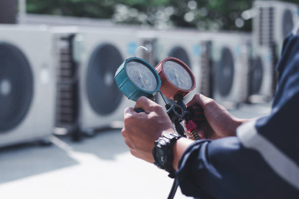 Technician checking air conditioning units with pressure gauges