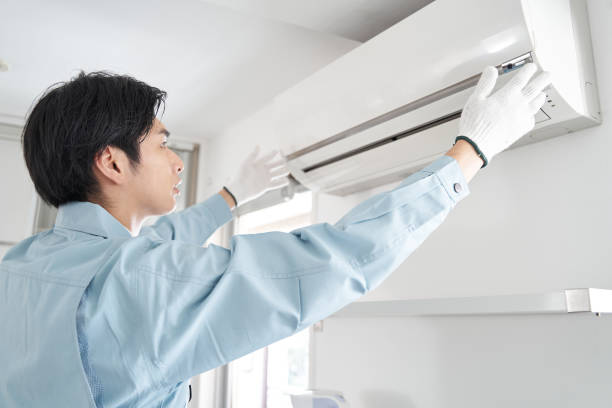 Technician installing or repairing a wall-mounted air conditioning unit