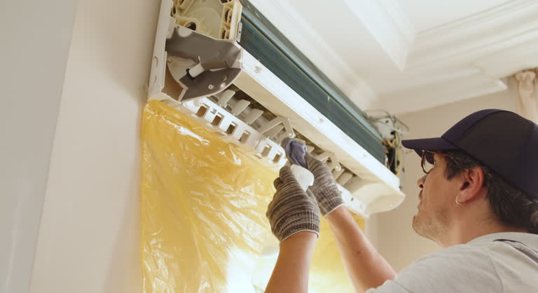 Technician installing or repairing air conditioning unit indoors