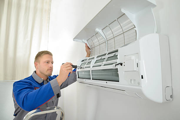Technician installing or repairing a wall-mounted air conditioning unit