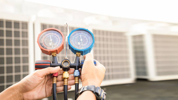 Technician checking air conditioning system with red and blue pressure gauges