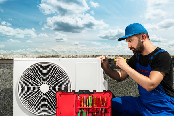 Technician repairing air conditioner unit on rooftop with tools