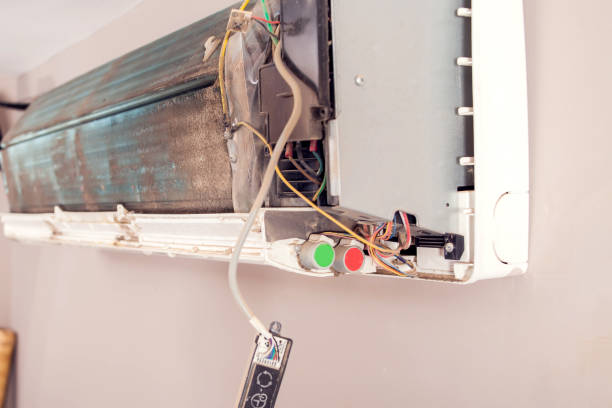 Old air conditioner unit with exposed wiring and colored electrical connectors