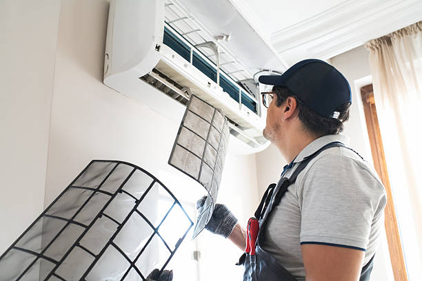 Technician inspecting and cleaning a wall-mounted air conditioning unit