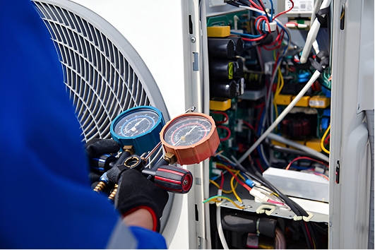 Technician checking pressure gauges while repairing an electrical system