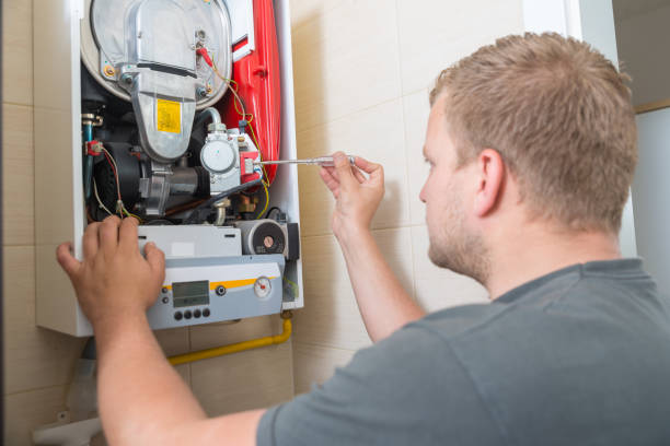Technician repairing or examining a wall-mounted boiler or heating system