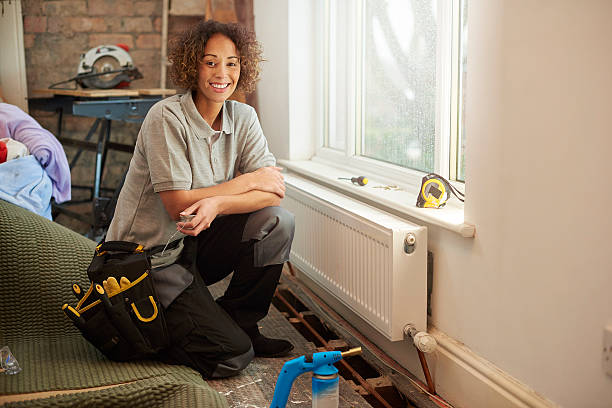 Smiling worker with tool belt sitting near window during home renovation
