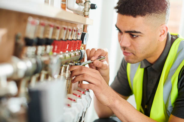 Technician in safety vest adjusting valves on industrial piping system