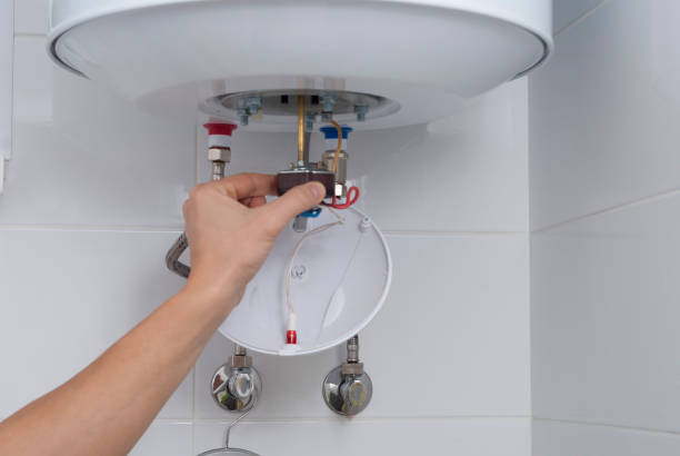 Hand adjusting temperature on a white electric water heater