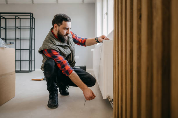 Man crouching and examining wall in room with moving boxes