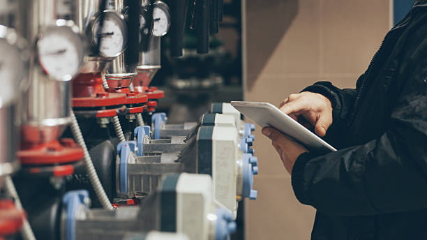 Technician using tablet to monitor industrial machinery with pressure gauges