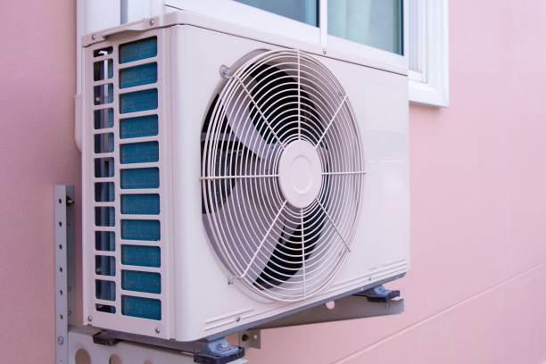 White air conditioning unit mounted on pink wall with large spinning fan