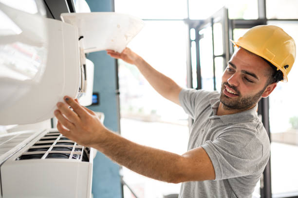 Worker in hard hat repairing or installing air conditioning unit