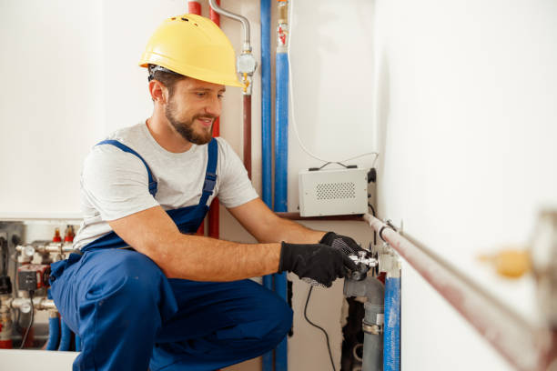 Worker in hard hat and gloves fixing industrial pipes and equipment