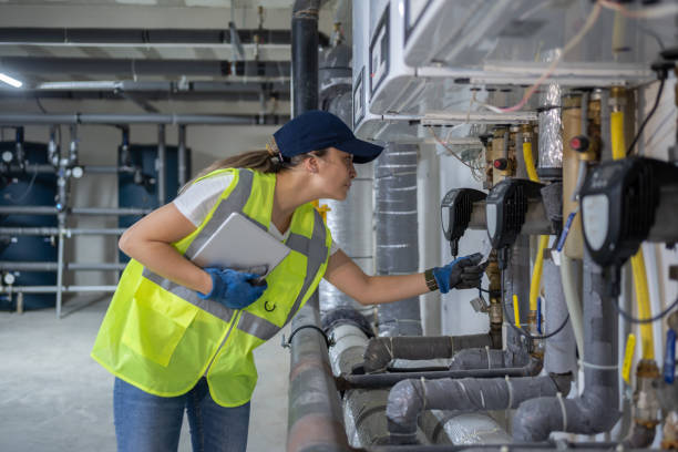 Technician in safety vest inspecting industrial pipes and machinery