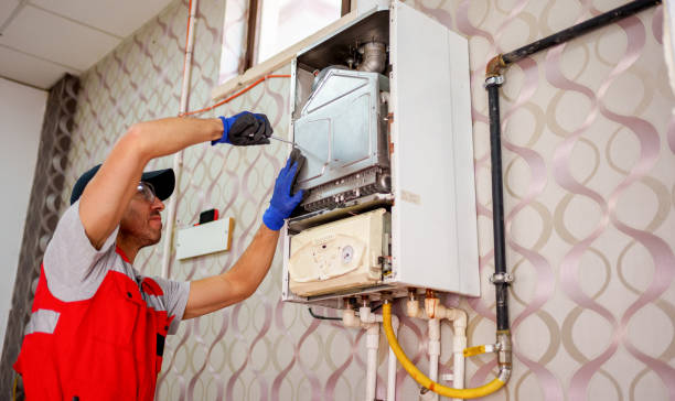 Technician in safety vest inspecting and repairing a wall-mounted heating system