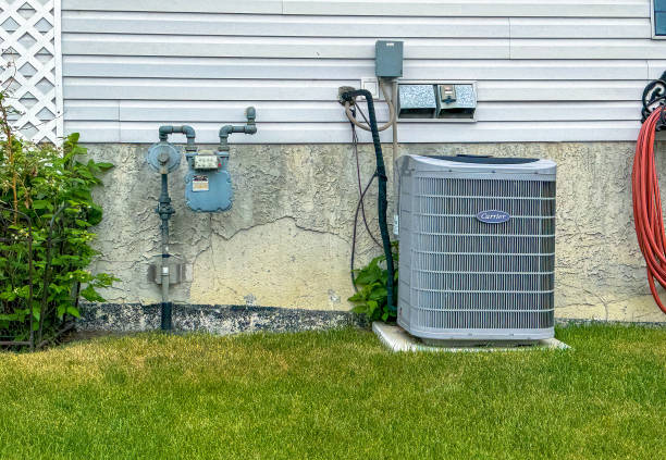 Air conditioning unit and utility meters on house exterior next to lawn