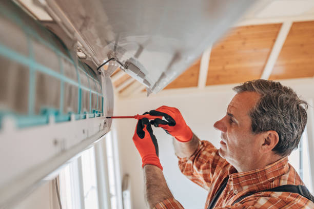 Man in red gloves repairing air conditioning unit indoors