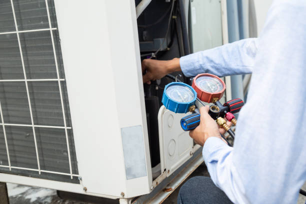 Technician checking air conditioning unit with pressure gauges