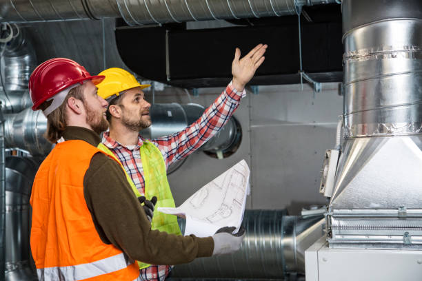 Construction workers in safety gear inspect industrial ventilation system