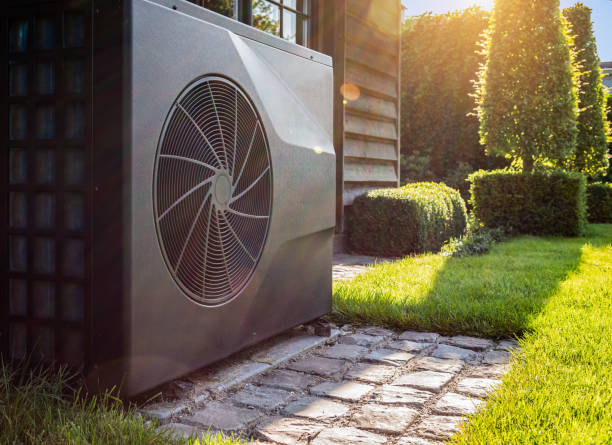 Modern heat pump installed outside home with sunny garden background