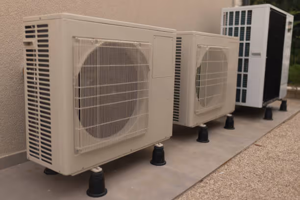 Multiple air conditioning units mounted on concrete stands outside building