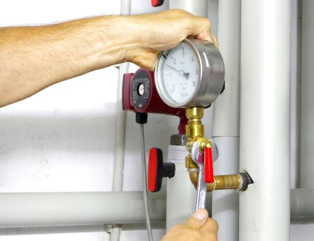 Hand adjusting pressure gauge on industrial piping system