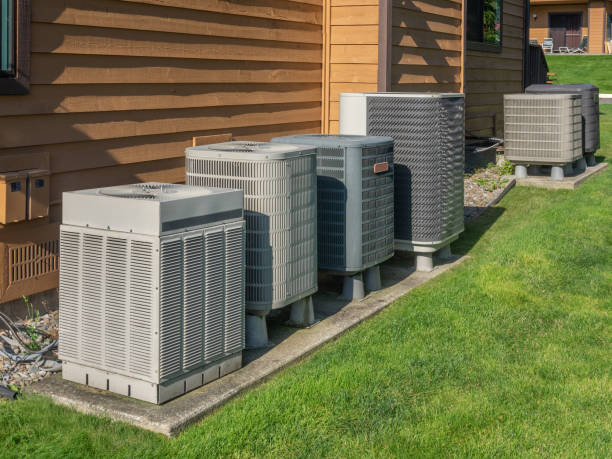 Multiple air conditioning units lined up next to a wooden house exterior