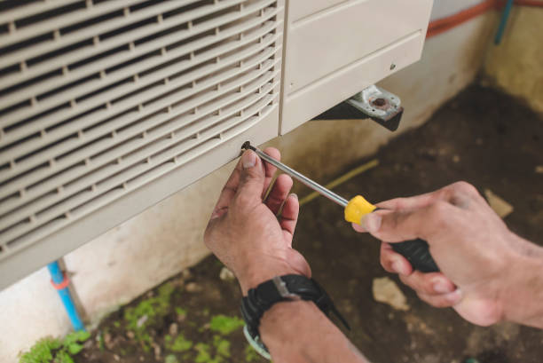 Hands using screwdriver to repair or install an air conditioning unit