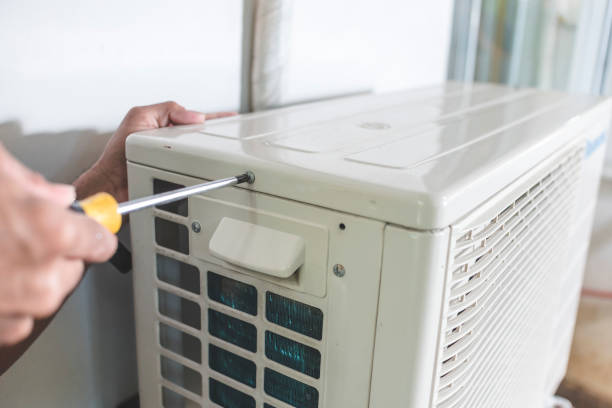 Technician using screwdriver to repair or maintain air conditioning unit