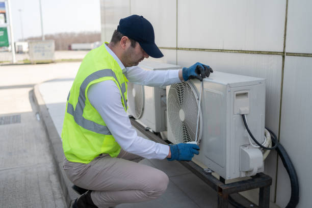 Technician in safety vest installing or repairing an air conditioning unit
