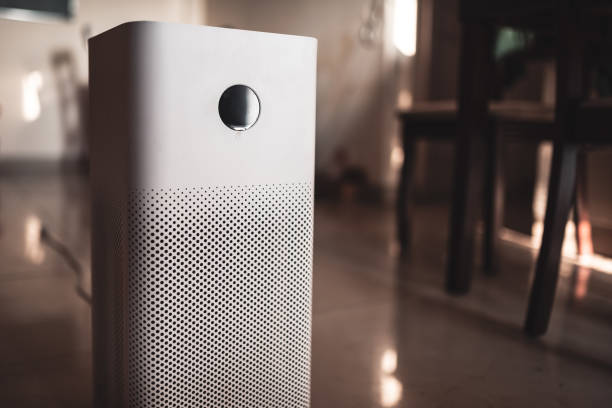 White air purifier with perforated design on wooden floor near furniture