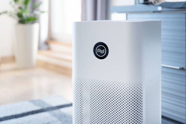 White air purifier with perforated design sitting in modern, bright room