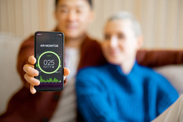 Person showing air quality monitor app with poor air quality reading