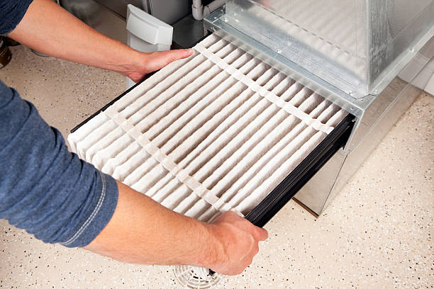 Person replacing a clean white air filter in HVAC system