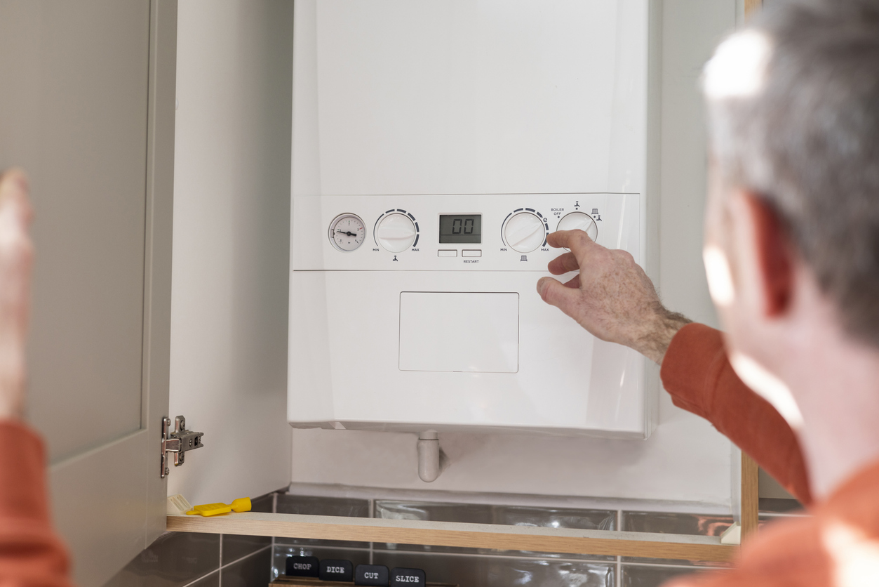 Hand adjusting settings on a white home heating boiler control panel