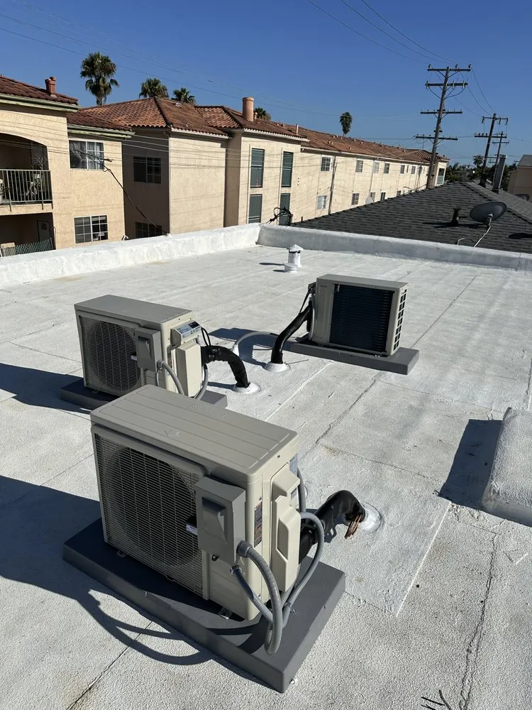 Air conditioning units on a flat roof with apartment buildings in background