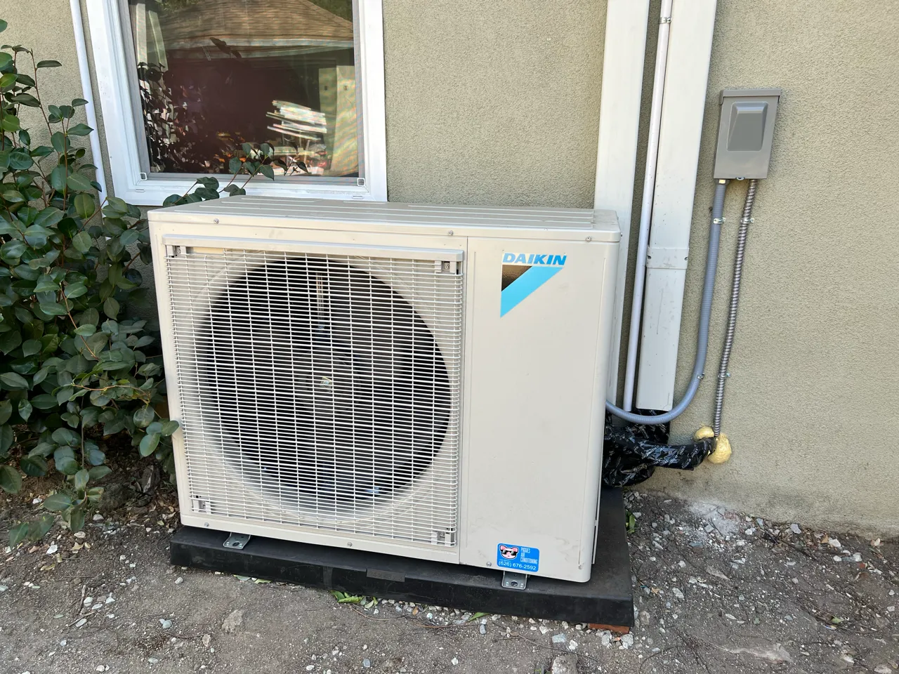 Daikin air conditioning unit mounted on exterior wall next to window