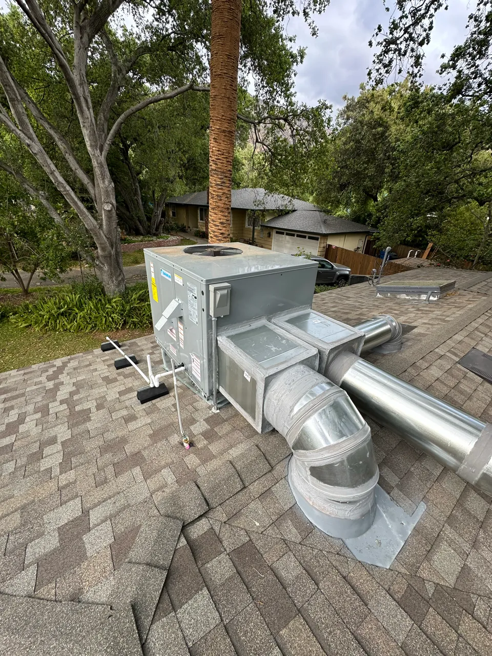 Large HVAC unit installed on residential roof with metal ductwork