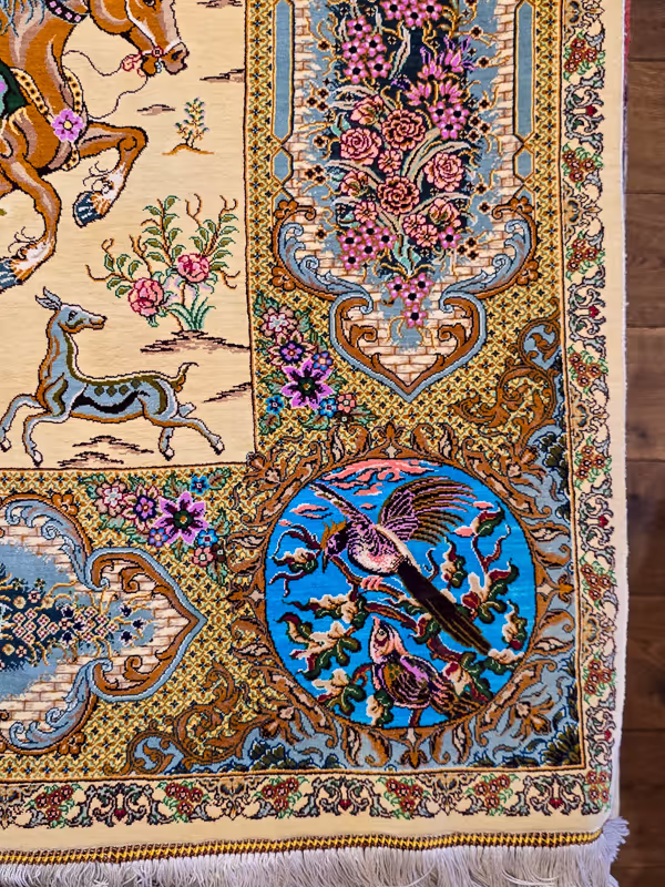 Ingewikkeld ontworpen tapijthoek met paarden, bloemen en vogels in levendige kleuren.