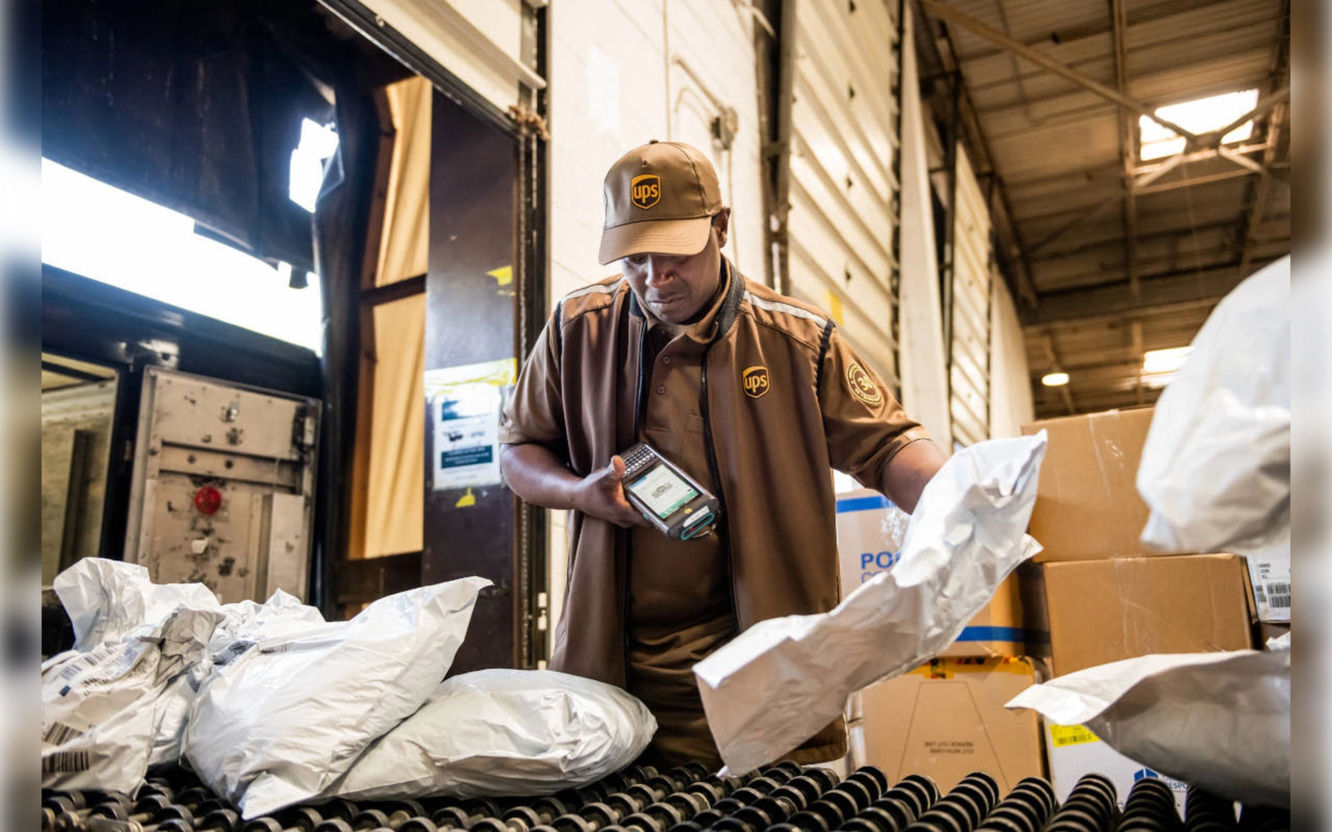 Ein UPS-Mitarbeiter scannt Pakete an einem Förderband im Logistikzentrum