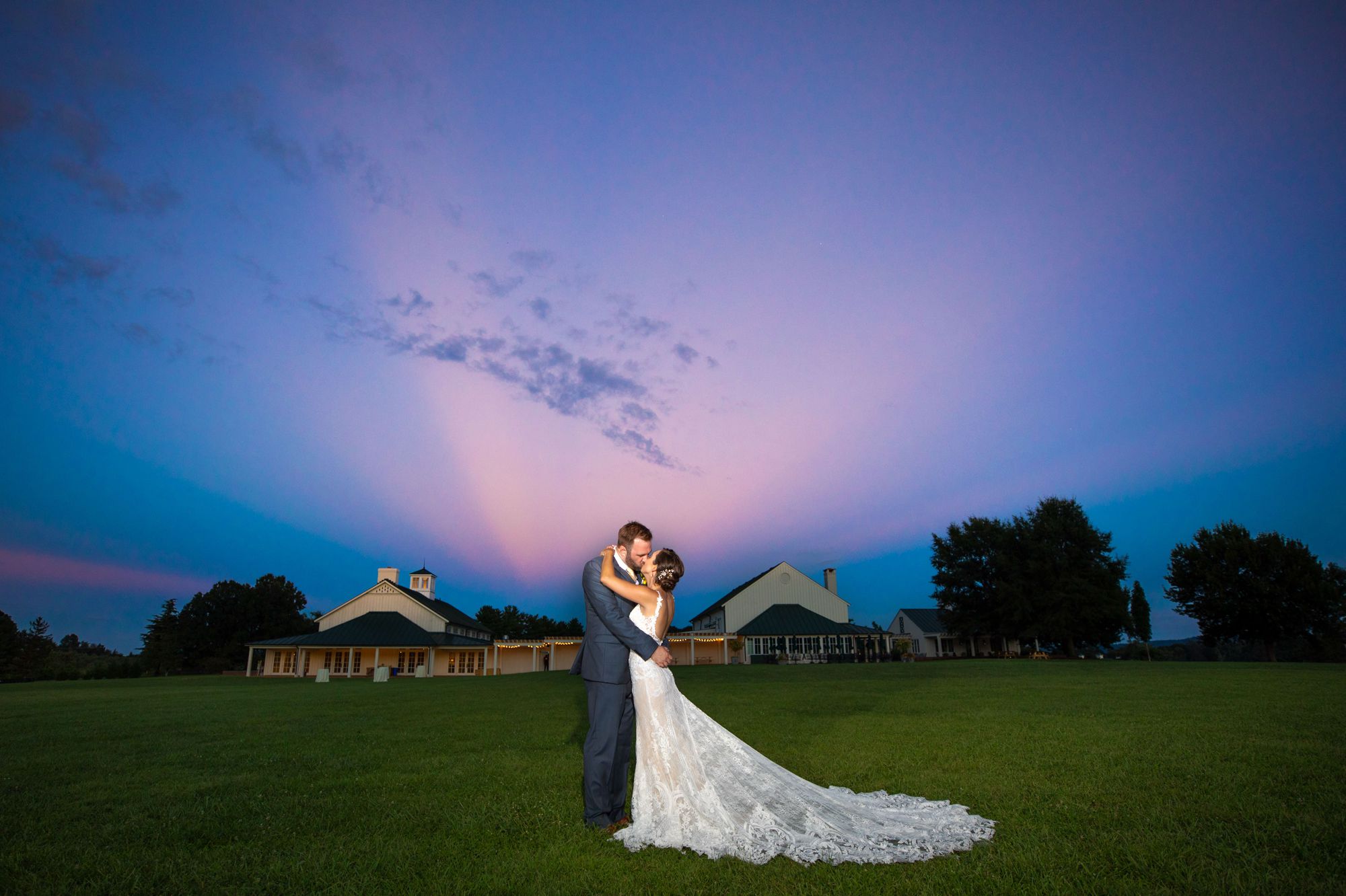 Couple kissing under the sunset on their wedding day at King Family Vineyard with the Carriage House in the background
