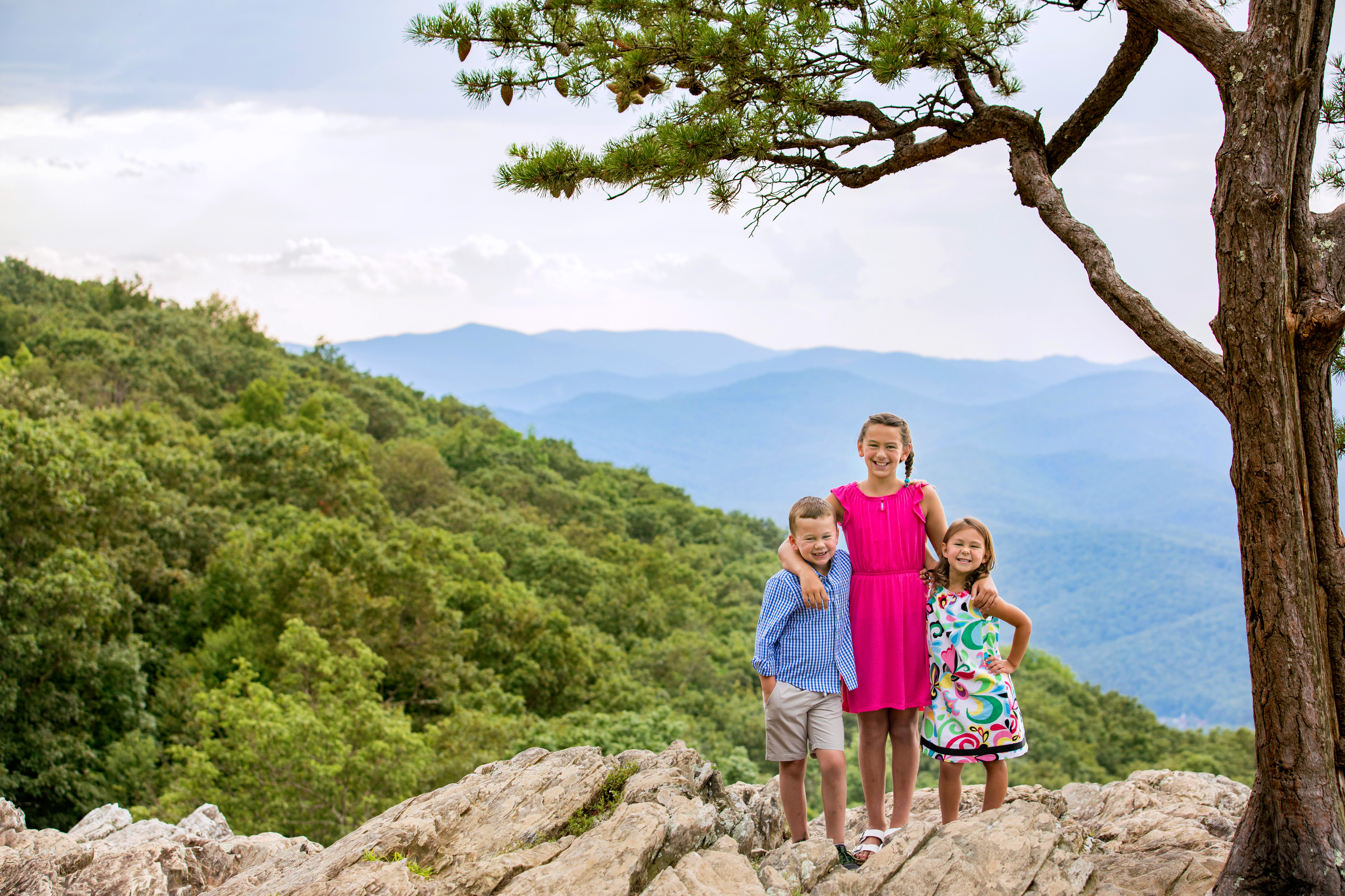 Three siblings pose for their summer family photos at Raven's Roost Overlook wearing coordinating bright colorful outfits