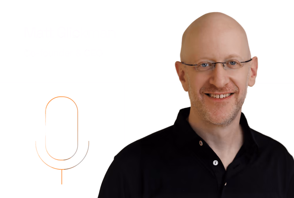 Headshot of a smiling bald man in glasses and a black polo shirt beside a microphone icon