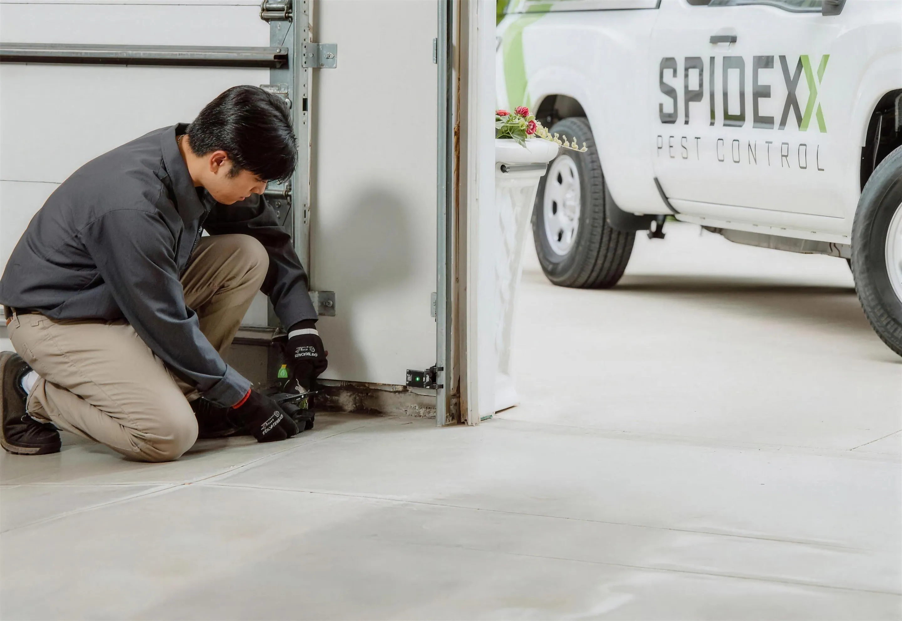A Spidexx technician treating a garage doorway