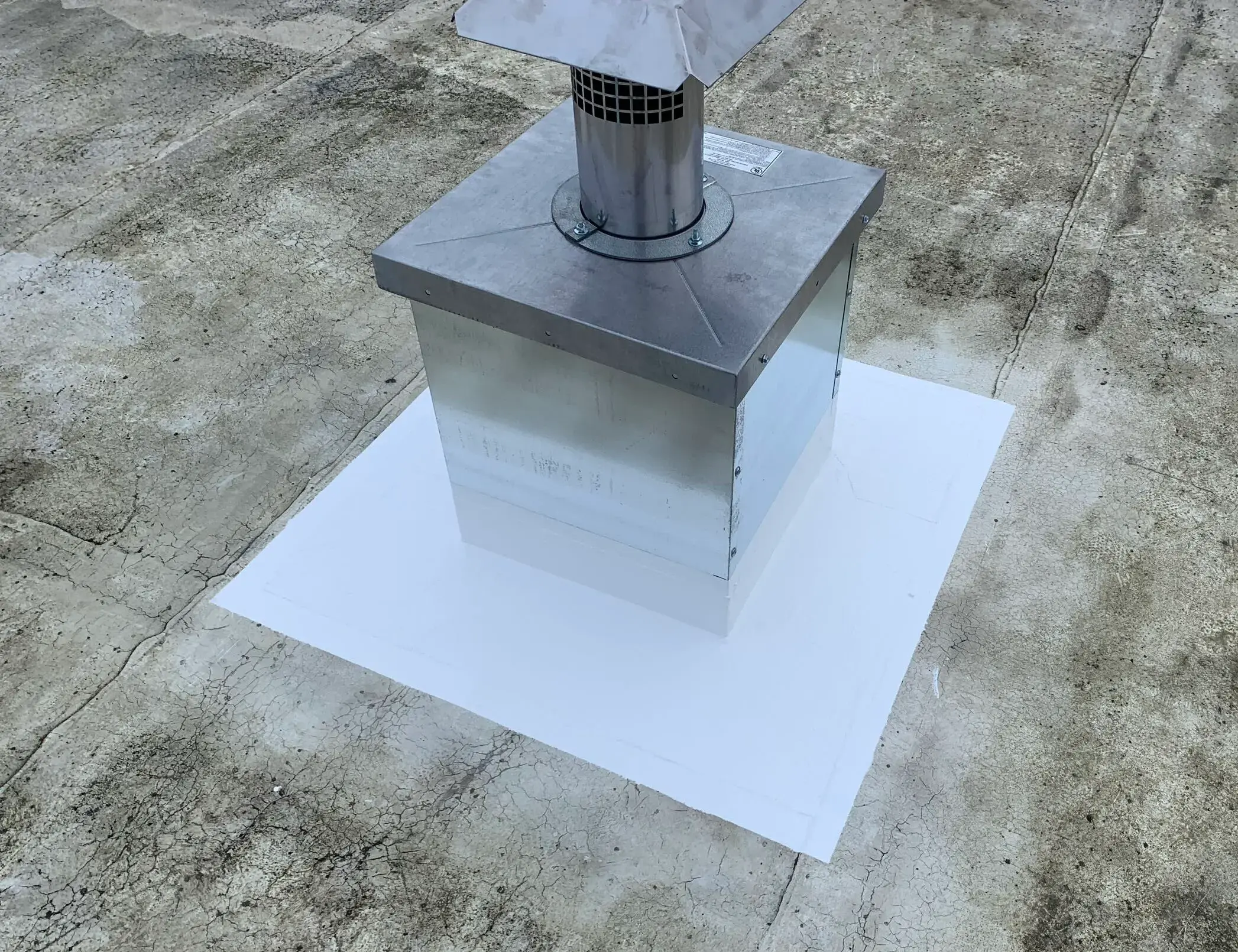 Silicone flashing around rooftop vent on a flat commercial roof with restored waterproofing membrane.