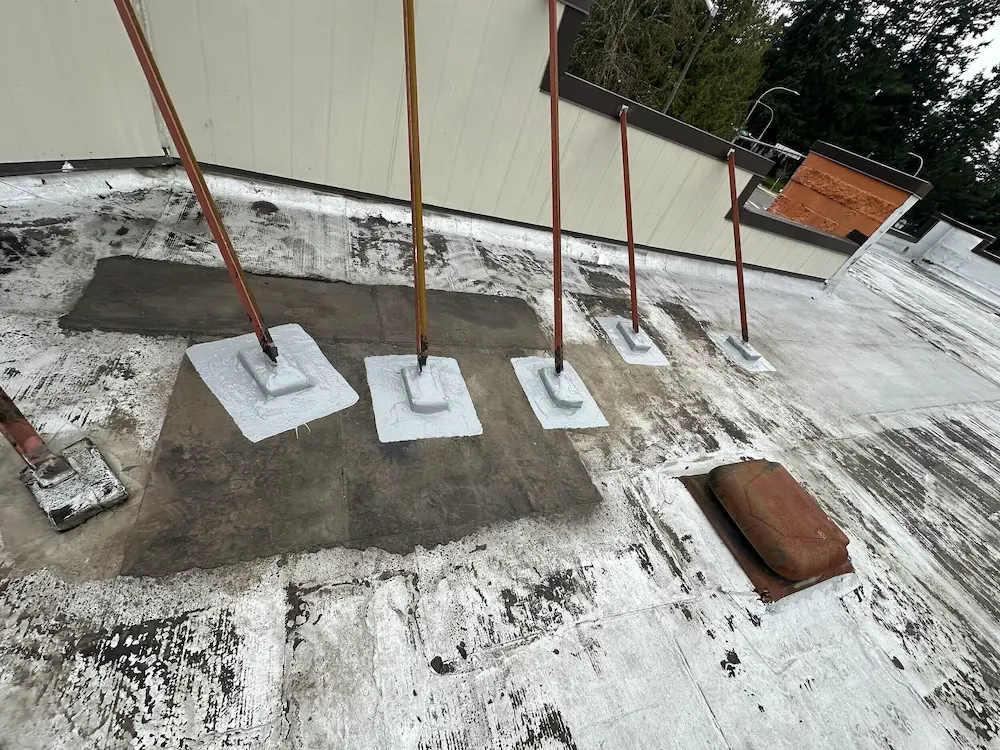 Seattle flat roof repair with silicone-sealed safety stanchion bases for long-term waterproofing and code compliance.