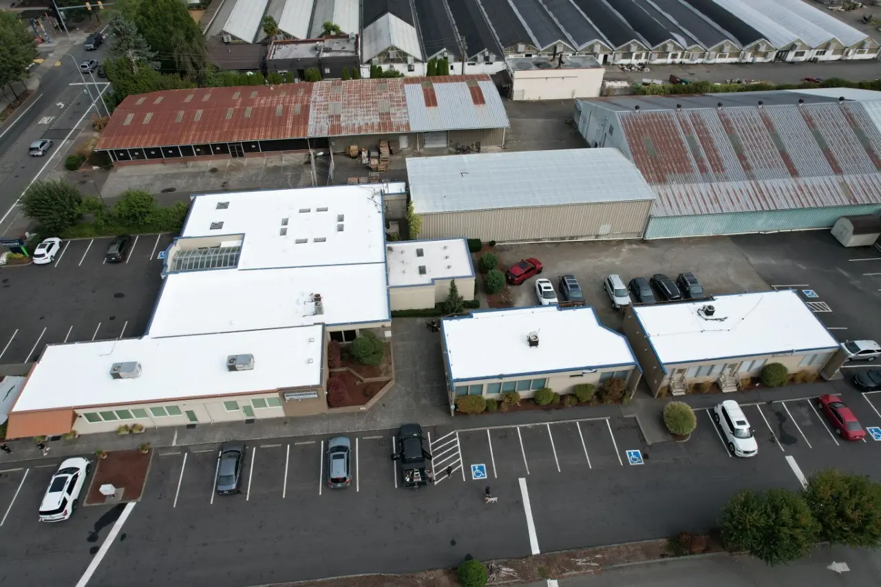 Aerial view of flat roof restoration on multiple commercial buildings — white membrane system installed for long-term protection and enhanced energy efficiency.