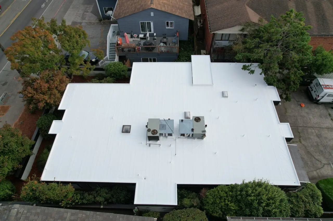 Flat roof restoration on residential property featuring seamless white membrane — revitalizing old roofing system for modern performance, weather protection, and efficiency.